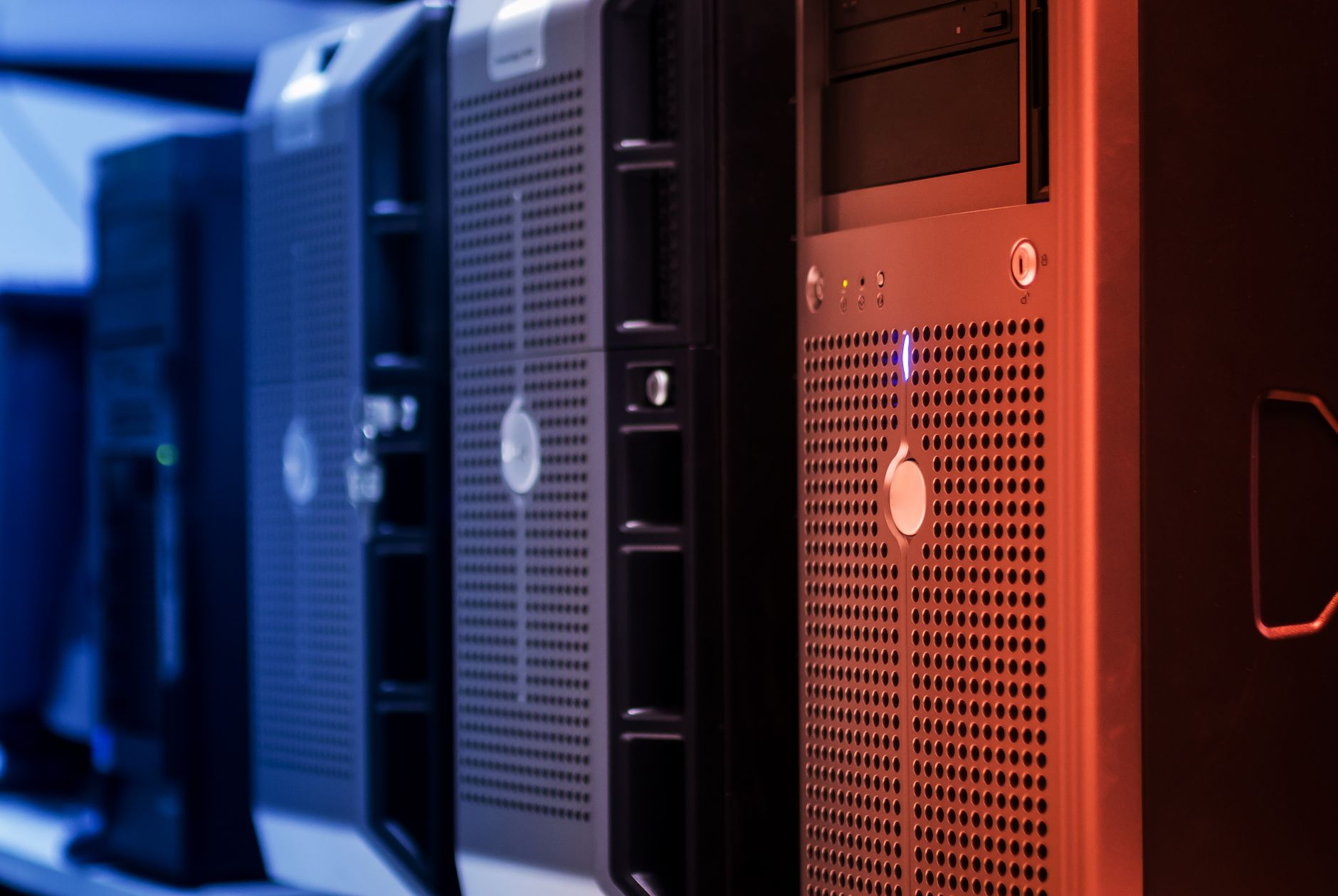Rad výpočtových serverov s perforovanými prednými panelmi v datacentre, osvetlený modrým a oranžovým svetlom